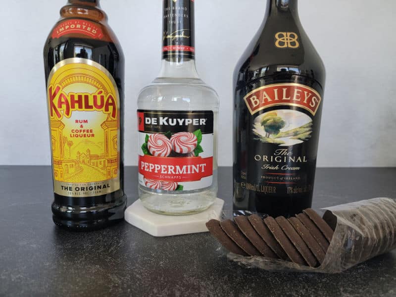 Kahlua, Peppermint Schnapps, and Baileys Irish Cream bottles next to a sleeve of Thin Mint Cookies