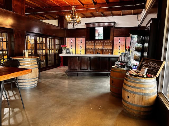 Winery tasting room with barrels and a large table for tasting