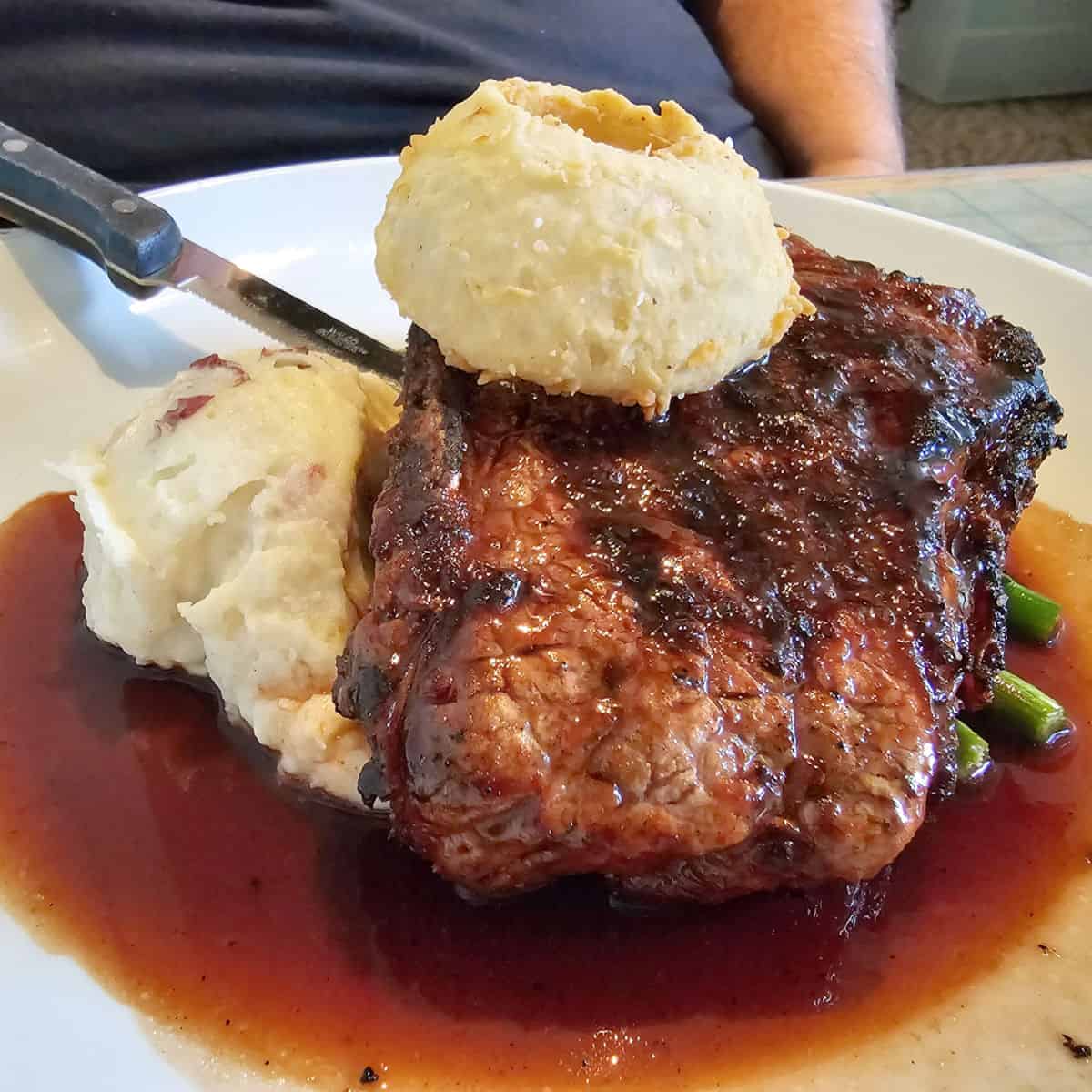 Ribeye topped with onion ring next to mashed potatoes