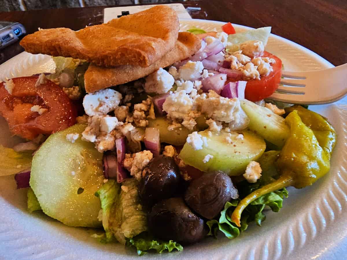 Greek salad in a white bowl with a fork on the side