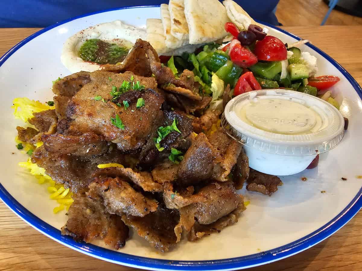 Gyro plate with tzatziki sauce and pita pieces.