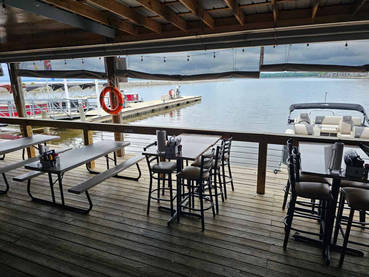 deck with tables with the water in the background and boats docked