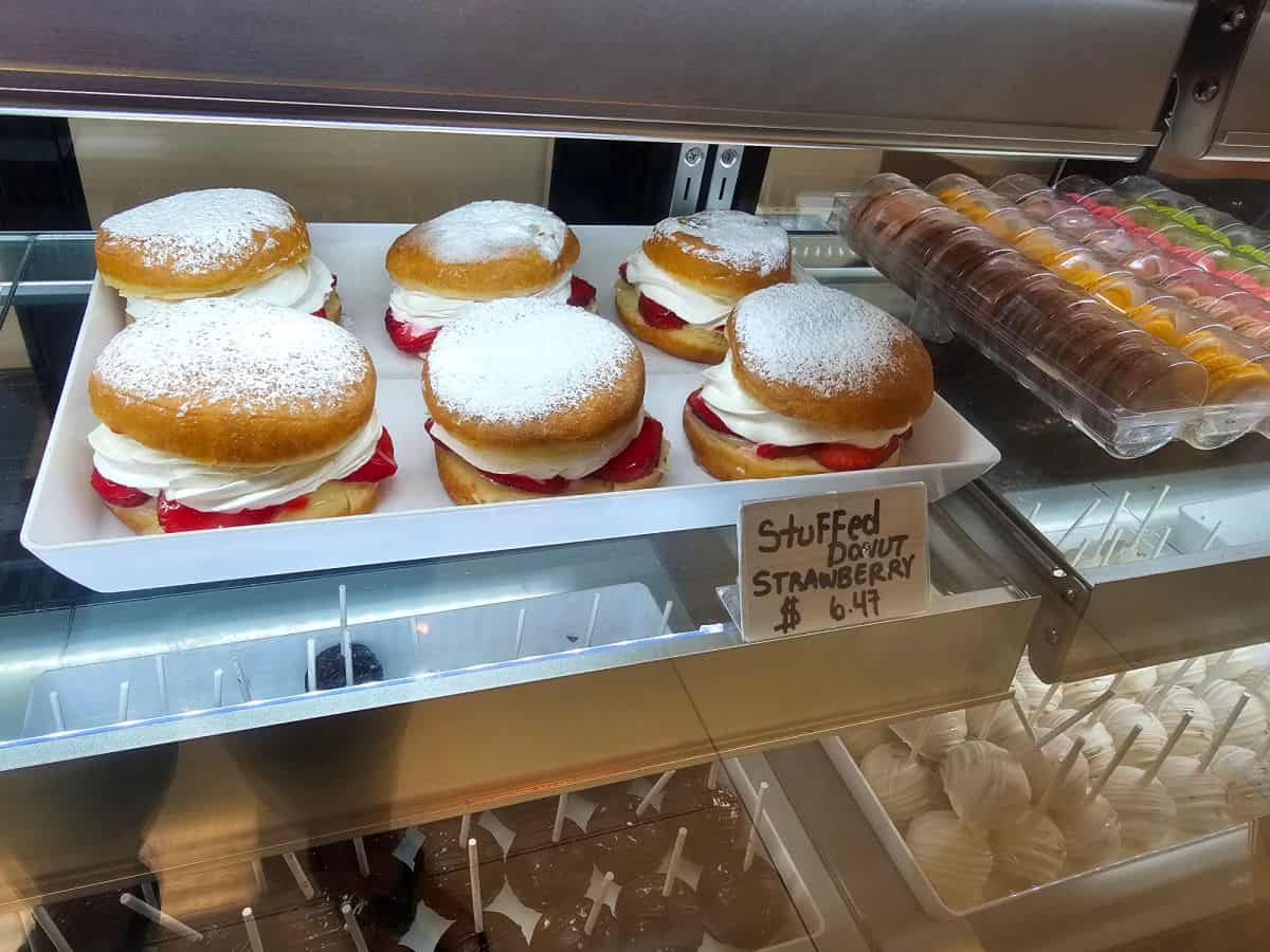 tray of Stuffed strawberry donuts in a display case