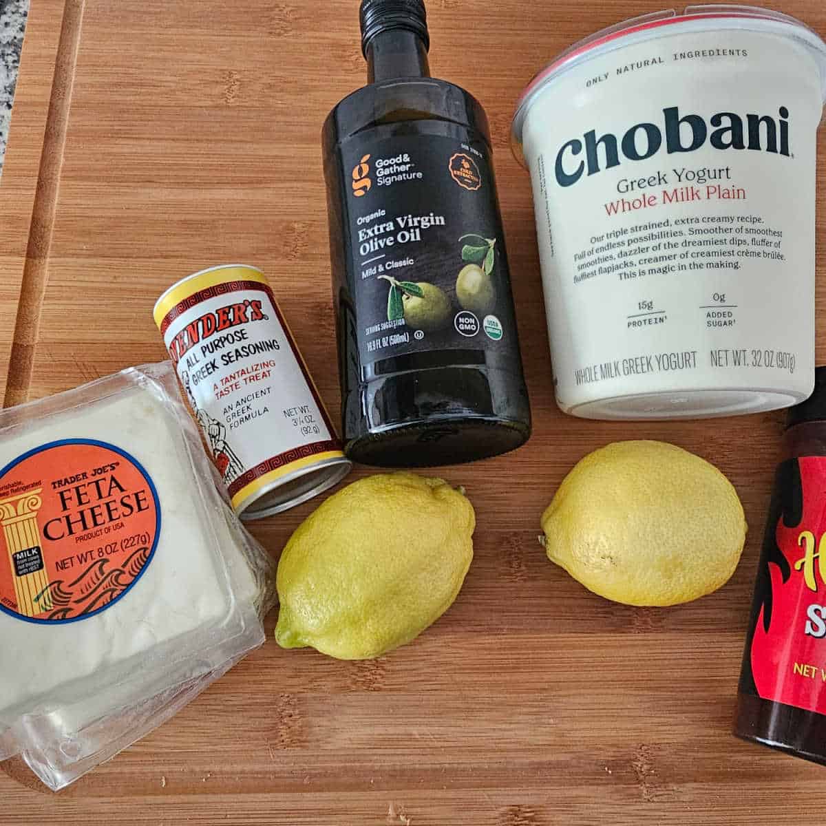 feta, Greek seasoning, olive oil, plain Greek yogurt, lemons on a cutting board