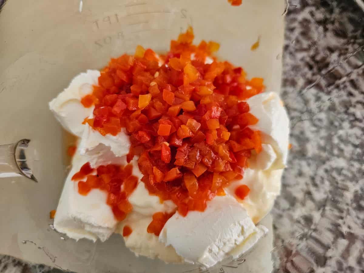 cream cheese cubes, mayo, and diced pimento peppers in a glass bowl